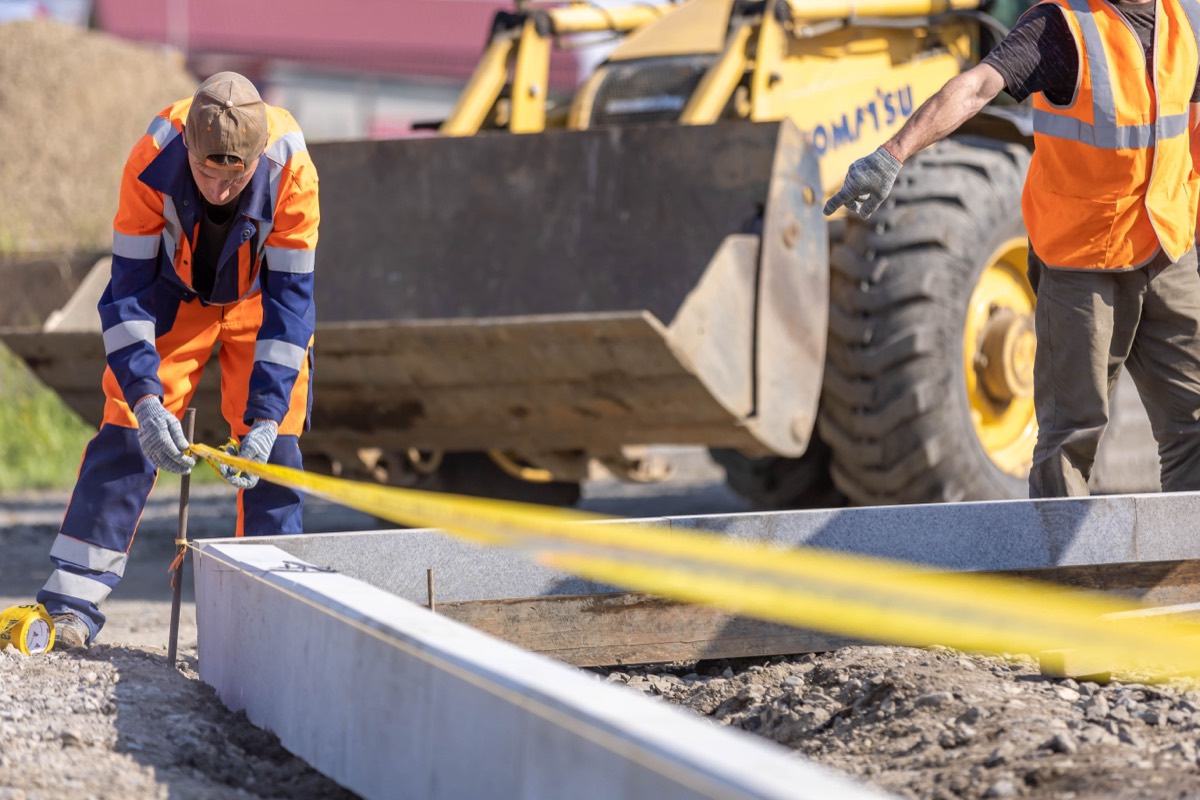 Ouvriers posant une bordure et balisant une zone de travaux dans l'Aisne